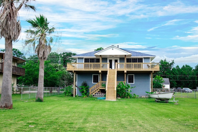 rear view of property featuring a lawn, a balcony, and a wooden deck