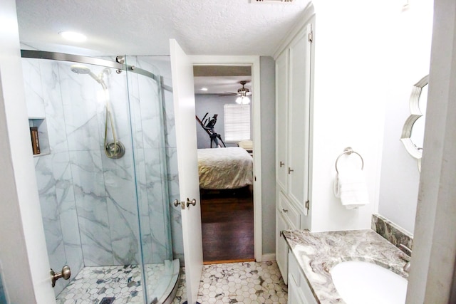 bathroom featuring hardwood / wood-style flooring, a shower with door, ceiling fan, vanity, and a textured ceiling