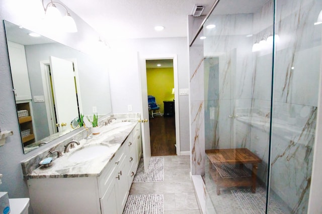 bathroom with a shower with shower door, large vanity, tile floors, and dual sinks