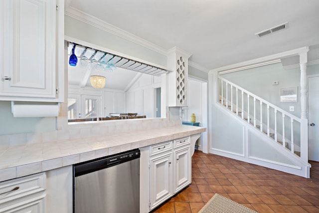 kitchen with stainless steel dishwasher, tile countertops, dark tile flooring, white cabinetry, and crown molding