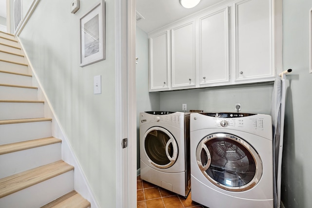 laundry room featuring light tile flooring, cabinets, and washer and clothes dryer