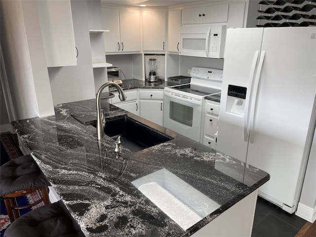 kitchen featuring kitchen peninsula, white appliances, white cabinetry, dark stone countertops, and sink