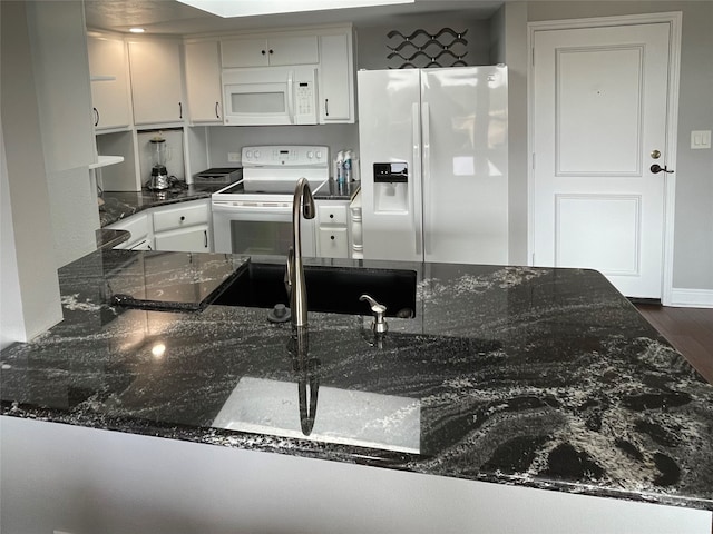 kitchen featuring kitchen peninsula, white appliances, dark stone countertops, dark wood-type flooring, and white cabinetry