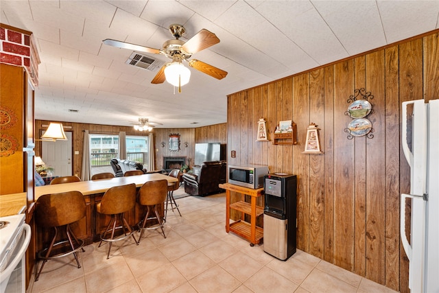 dining room featuring wood walls, a fireplace, and ceiling fan