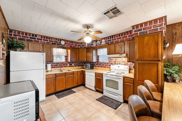 kitchen featuring brick wall, white appliances, ceiling fan, sink, and light tile patterned floors