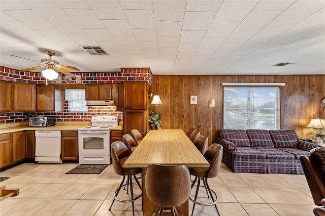 kitchen featuring light tile patterned floors, white appliances, tasteful backsplash, and wooden walls