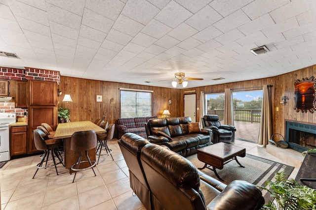 living room featuring light tile patterned floors, plenty of natural light, and wood walls