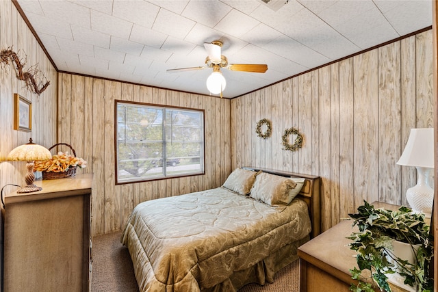 carpeted bedroom with ceiling fan, crown molding, and wood walls