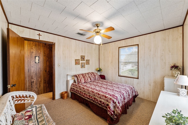 bedroom with carpet flooring, ceiling fan, and wood walls