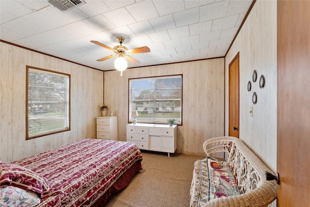 carpeted bedroom featuring ceiling fan and wooden walls