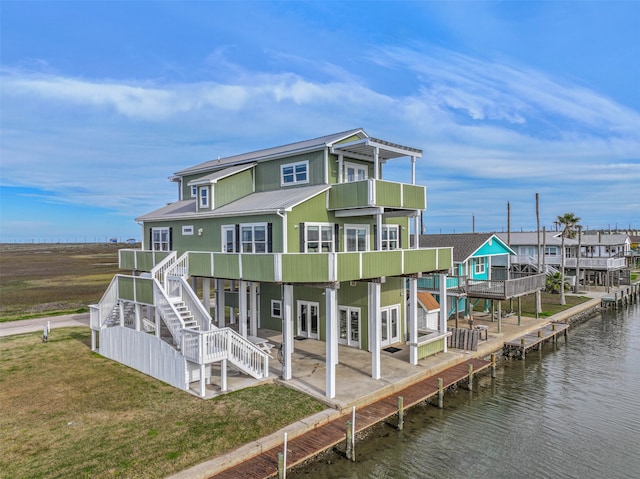 rear view of property with a patio area, a deck with water view, and a yard