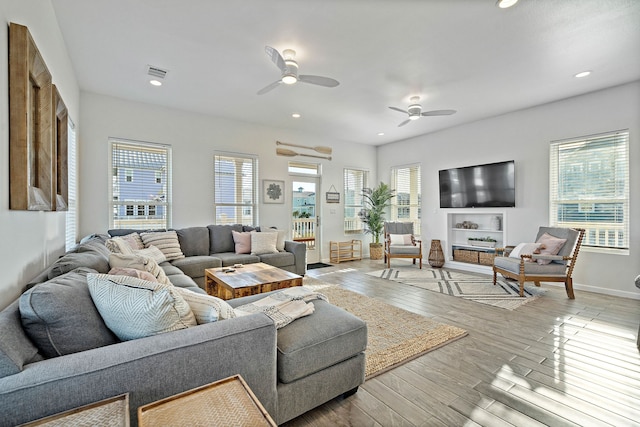 living room with a wealth of natural light, light hardwood / wood-style flooring, and ceiling fan