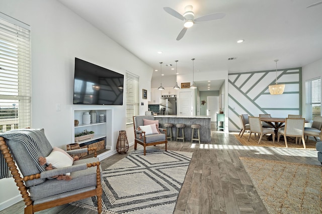 living room featuring ceiling fan, a wealth of natural light, and dark hardwood / wood-style floors