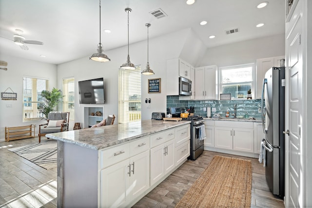 kitchen with pendant lighting, white cabinets, appliances with stainless steel finishes, tasteful backsplash, and ceiling fan