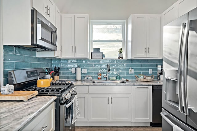 kitchen featuring backsplash, appliances with stainless steel finishes, white cabinets, and sink