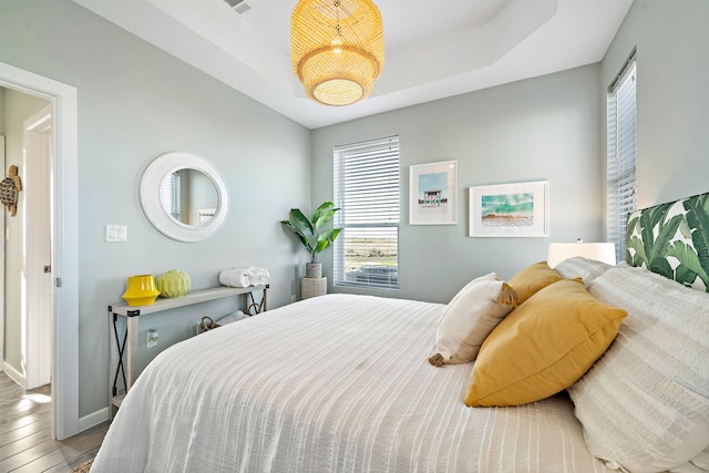 bedroom with hardwood / wood-style floors and a raised ceiling