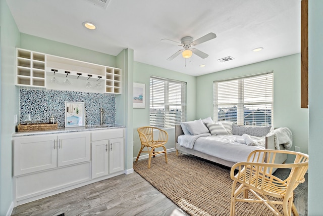 bedroom featuring light hardwood / wood-style flooring, sink, and ceiling fan