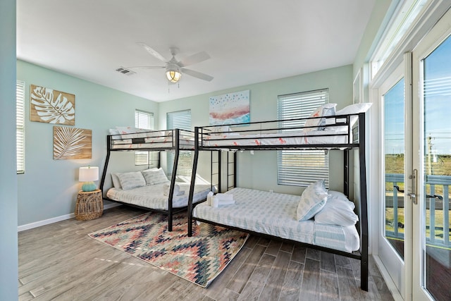 bedroom with hardwood / wood-style floors, ceiling fan, and multiple windows