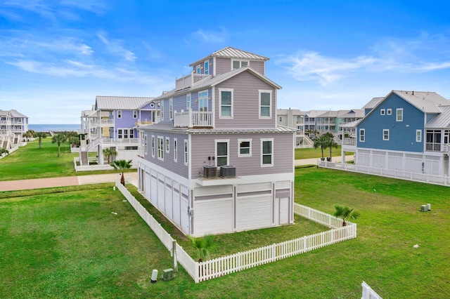 rear view of property featuring a yard, a garage, a balcony, and central AC unit