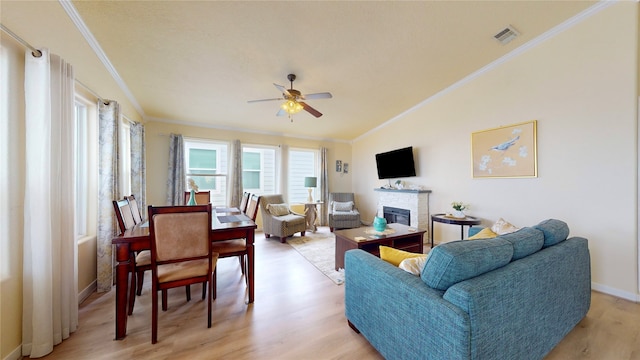 living room with a fireplace, ceiling fan, crown molding, lofted ceiling, and light wood-type flooring