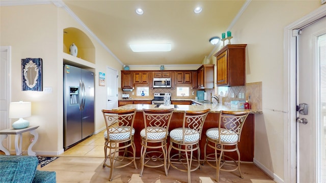 kitchen with appliances with stainless steel finishes, backsplash, a kitchen bar, light hardwood / wood-style floors, and sink