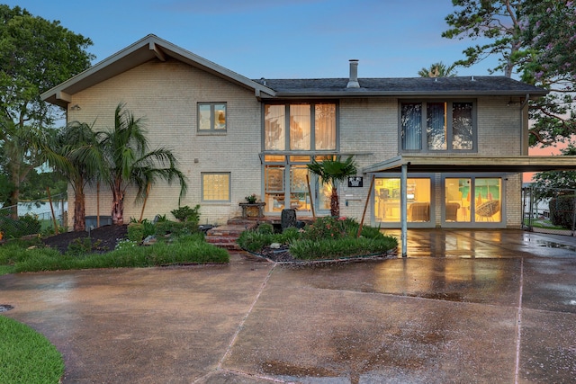 back house at dusk featuring a patio