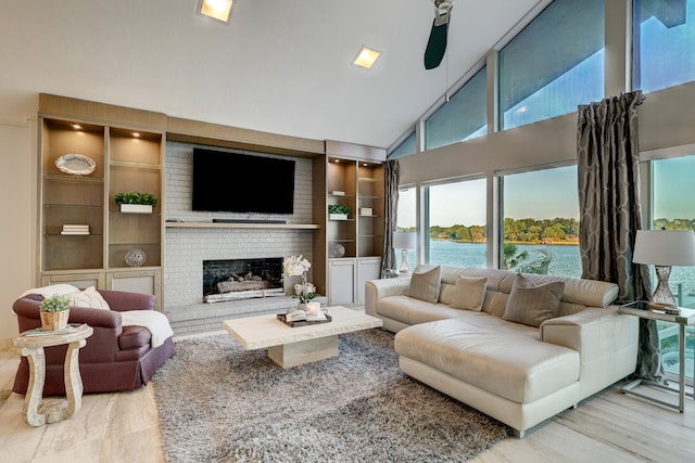 living room featuring built in shelves, hardwood / wood-style floors, high vaulted ceiling, and a brick fireplace