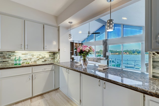 kitchen featuring white cabinetry, decorative light fixtures, and dark stone countertops