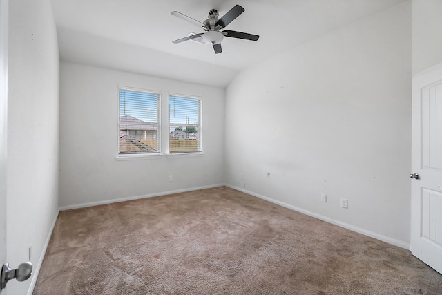 empty room featuring lofted ceiling, ceiling fan, and light colored carpet