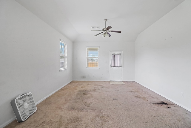 spare room with ceiling fan, vaulted ceiling, and light colored carpet