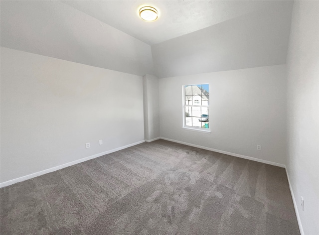 unfurnished room featuring dark carpet and lofted ceiling