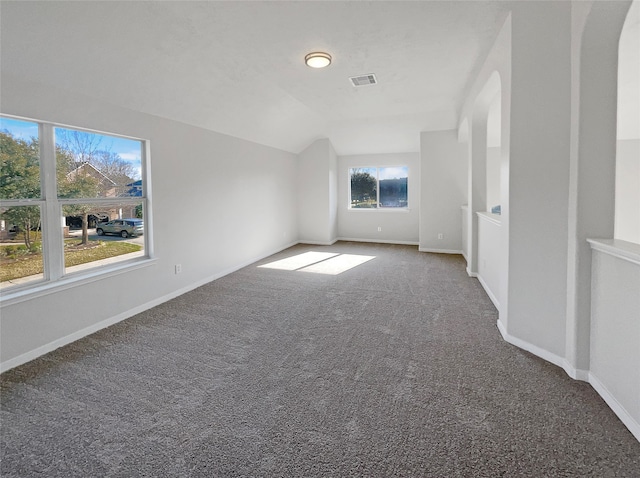 empty room with dark colored carpet and plenty of natural light