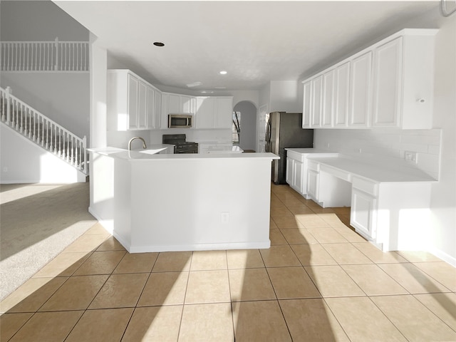 kitchen with appliances with stainless steel finishes, tasteful backsplash, white cabinets, and light tile floors