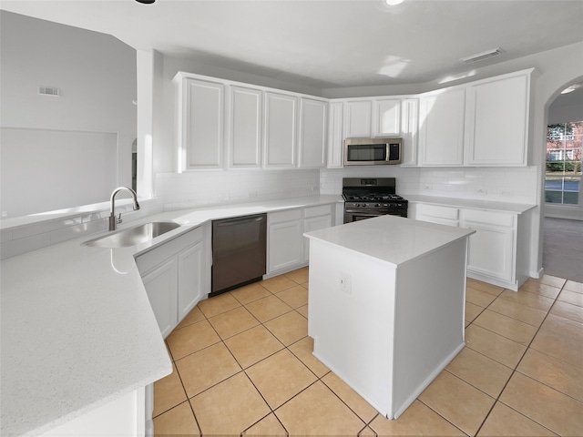 kitchen featuring sink, stainless steel appliances, tasteful backsplash, white cabinetry, and a center island