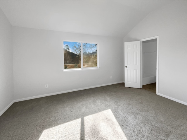 unfurnished room with lofted ceiling and dark carpet