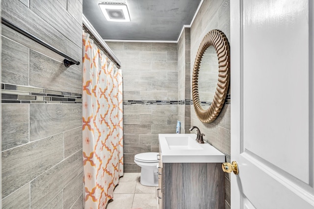 bathroom with tile walls, toilet, vanity, and tile flooring