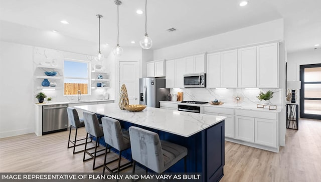 kitchen with white cabinetry, a center island, hanging light fixtures, stainless steel appliances, and light hardwood / wood-style floors