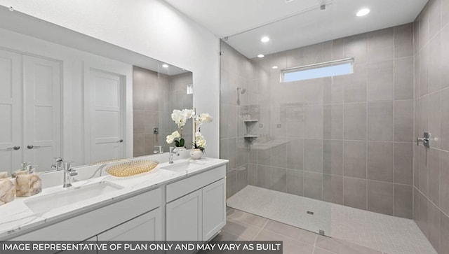 bathroom with tile patterned flooring, vanity, and tiled shower