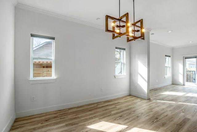 unfurnished room with light hardwood / wood-style flooring, a notable chandelier, ornamental molding, and a healthy amount of sunlight