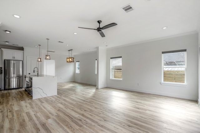 interior space featuring ornamental molding, light hardwood / wood-style floors, a wealth of natural light, and ceiling fan