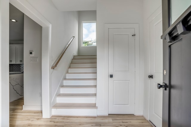 stairway with light hardwood / wood-style floors