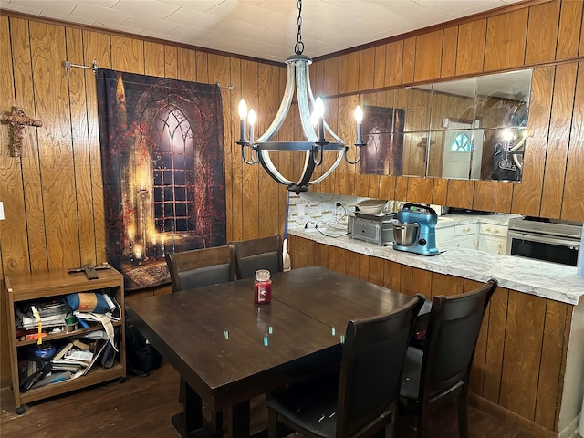 dining space with dark hardwood / wood-style flooring, wooden walls, and a notable chandelier