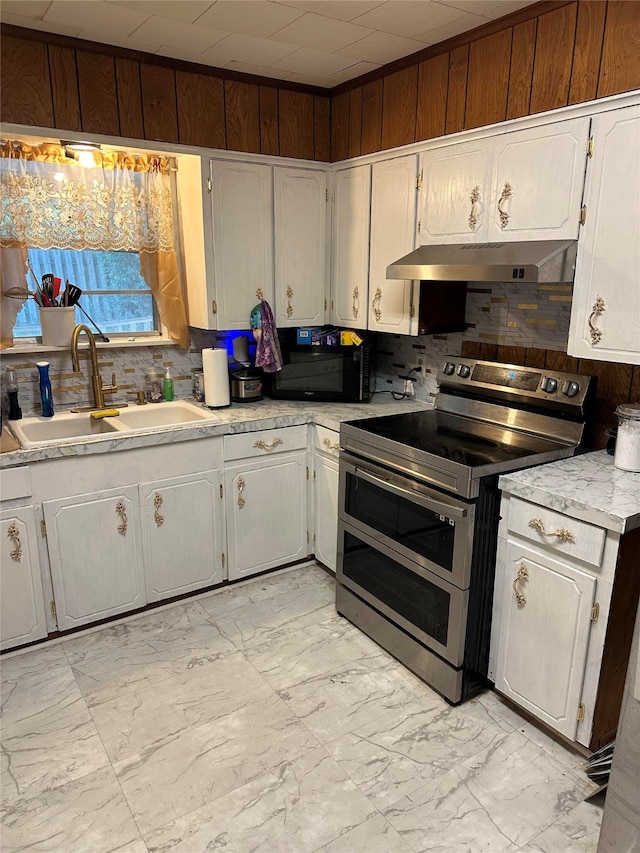 kitchen with decorative backsplash, wall chimney exhaust hood, sink, range with two ovens, and light tile patterned floors