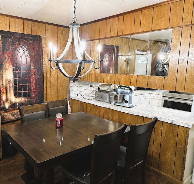 dining space with wood walls, a notable chandelier, and dark hardwood / wood-style flooring