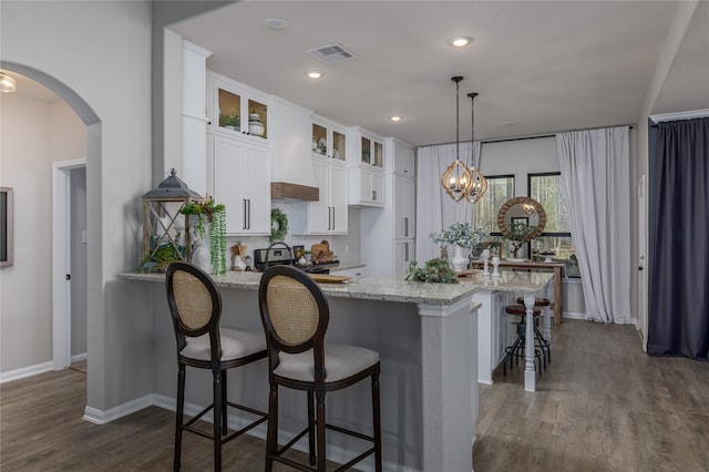 kitchen with dark hardwood / wood-style floors, light stone countertops, white cabinetry, and hanging light fixtures