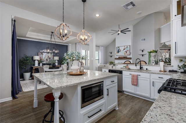 kitchen with sink, light stone counters, a breakfast bar, white cabinets, and appliances with stainless steel finishes