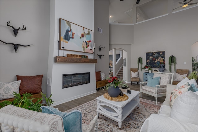 living room with ceiling fan, hardwood / wood-style floors, and a high ceiling