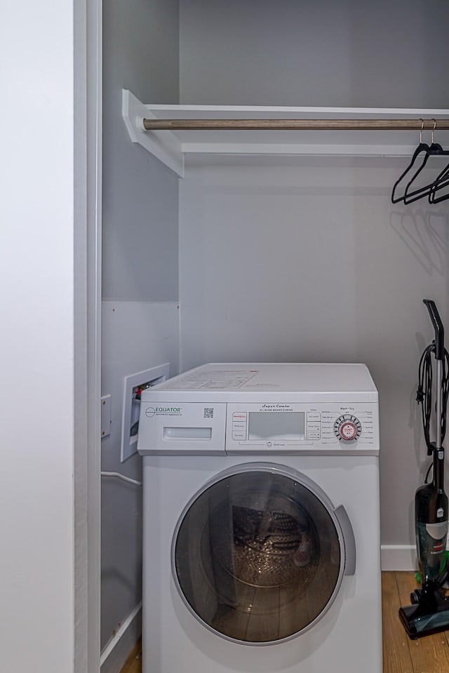 clothes washing area with hardwood / wood-style flooring and washer / clothes dryer