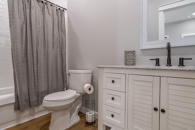 full bathroom featuring hardwood / wood-style flooring, shower / tub combo with curtain, vanity, and toilet