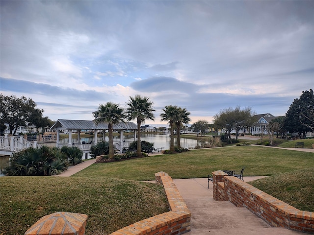 view of property's community with a water view and a lawn